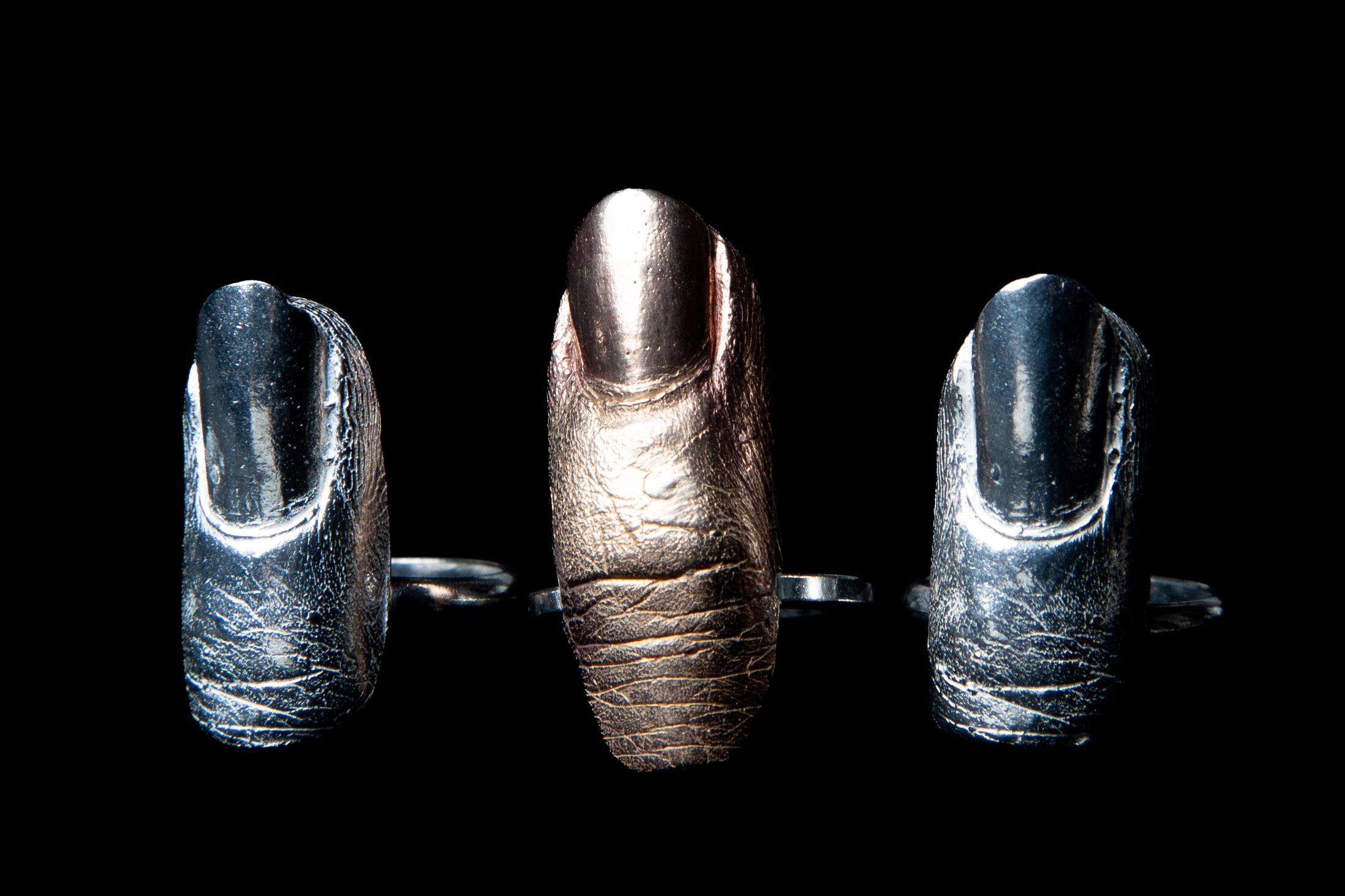 Three cast finger rings — two in sterling silver, one in bronze